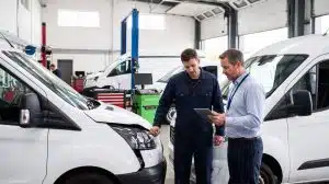 A fleet manager using a tablet to assess repair costs and downtime with a mechanic, highlighting the financial impact of delayed first notice of loss (FNOL).