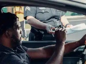 A driver receiving a traffic citation from a police officer during a roadside stop, representing the importance of real-time MVR monitoring.