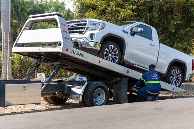 Flatbed tow truck loading a commercial pickup truck for accident recovery.