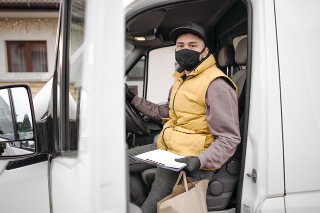 Commercial fleet driver in van cab holding clipboard for safety program.